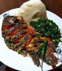 A plate of ugali served with sukuma wiki and fried fish